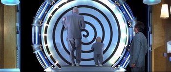 Movie still from “Austin Powers: The Spy Who Shagged Me” (1999), directed by Jay Roach – An older man and a small child standing in front of a spiraling wall; Wide shot, Overhead angle
