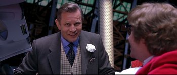 Movie still from “Austin Powers: The Spy Who Shagged Me” (1999), directed by Jay Roach – A man in a suit and tie smiling for the camera; Close Up shot, Over the shoulder angle