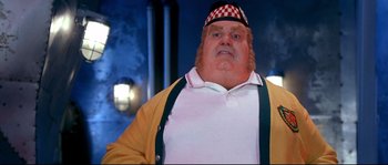 Movie still from “Austin Powers: The Spy Who Shagged Me” (1999), directed by Jay Roach – A man with a checkered hat is standing in front of a building; Close Up shot, Low angle