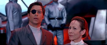 Movie still from “Austin Powers: The Spy Who Shagged Me” (1999), directed by Jay Roach – A man and a woman wearing eye glasses and a suit; Close Up shot, Over the shoulder angle