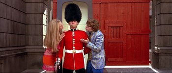 Movie still from “Austin Powers: The Spy Who Shagged Me” (1999), directed by Jay Roach – Two women and a man are standing next to a statue of a man; Medium shot, Low angle