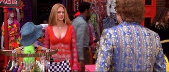 Movie still from “Austin Powers: The Spy Who Shagged Me” (1999), directed by Jay Roach – A woman in a red dress standing in front of a crowd; Medium shot, Over the shoulder angle