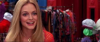 Movie still from “Austin Powers: The Spy Who Shagged Me” (1999), directed by Jay Roach – A woman smiling in front of a rack of clothes; Close Up shot, Over the shoulder angle