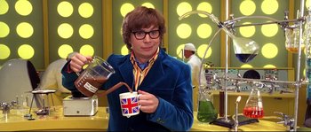 Movie still from “Austin Powers: The Spy Who Shagged Me” (1999), directed by Jay Roach – A person holding a cup of coffee in a room; Medium shot, High angle