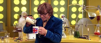 Movie still from “Austin Powers: The Spy Who Shagged Me” (1999), directed by Jay Roach – A man in a blue jacket holding a mug; Medium shot, High angle