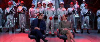 Movie still from “Austin Powers: The Spy Who Shagged Me” (1999), directed by Jay Roach – A group of men and women dressed in silver suits; Wide shot, Low angle