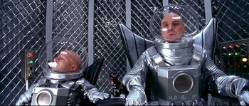 Movie still from “Austin Powers: The Spy Who Shagged Me” (1999), directed by Jay Roach – Two men in space suits sitting next to each other; Medium shot, Low angle