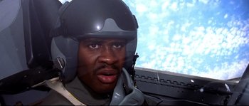 Movie still from “Austin Powers: The Spy Who Shagged Me” (1999), directed by Jay Roach – A man wearing a helmet and holding a cell phone to his ear while sitting in an airplane; Close Up shot, Low angle