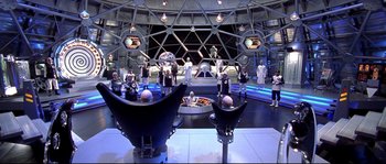 Movie still from “Austin Powers: The Spy Who Shagged Me” (1999), directed by Jay Roach – A group of people standing around in a room; Wide shot, High angle