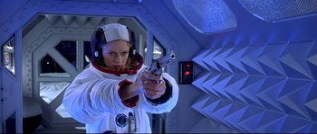 Movie still from “Austin Powers: The Spy Who Shagged Me” (1999), directed by Jay Roach – A girl in a spacesuit is holding a gun; Medium shot, Low angle