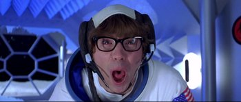 Movie still from “Austin Powers: The Spy Who Shagged Me” (1999), directed by Jay Roach – A man with glasses and a helmet is wearing headphones; Close Up shot, Overhead angle