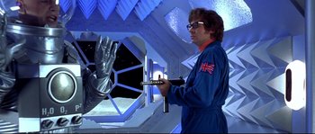 Movie still from “Austin Powers: The Spy Who Shagged Me” (1999), directed by Jay Roach – A man in a spacesuit holding a pair of scissors; Medium shot, Low angle