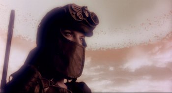 Movie still from “Avalon” (2001), directed by Mamoru Oshii – A person wearing a helmet and a face mask with binoculars on top of it; Close Up shot, Low angle