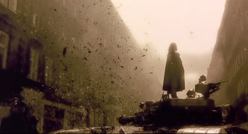 Movie still from “Avalon” (2001), directed by Mamoru Oshii – A person standing on top of a building near a bunch of debris; Wide shot, Low angle