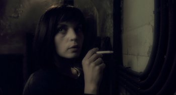 Movie still from “Avalon” (2001), directed by Mamoru Oshii – A woman holding a cigarette in her hand; Close Up shot, Over the shoulder angle