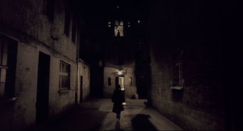 Movie still from “Avalon” (2001), directed by Mamoru Oshii – A person with an umbrella walking down a dark alley; Extreme Wide shot, Low angle