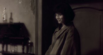 Movie still from “Avalon” (2001), directed by Mamoru Oshii – A woman with glasses is standing in front of a window; Close Up shot, Over the shoulder angle