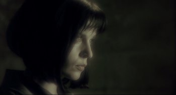 Movie still from “Avalon” (2001), directed by Mamoru Oshii – A woman is looking into the distance in a dimly - lit room; Close Up shot, Low angle