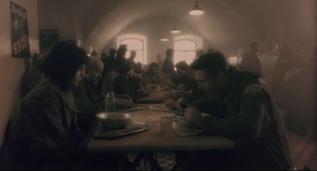 Movie still from “Avalon” (2001), directed by Mamoru Oshii – A group of people sitting at a table eating food; Wide shot, High angle