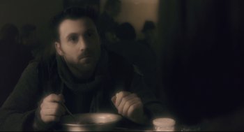 Movie still from “Avalon” (2001), directed by Mamoru Oshii – A man sitting at a table with a bowl of soup; Close Up shot, Over the shoulder angle