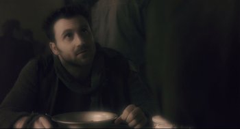 Movie still from “Avalon” (2001), directed by Mamoru Oshii – A man sitting at a table with a plate in front of him; Close Up shot, Over the shoulder angle