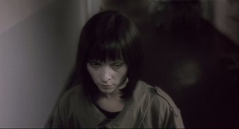 Movie still from “Avalon” (2001), directed by Mamoru Oshii – A woman in a dark room looking sad; Close Up shot, High angle