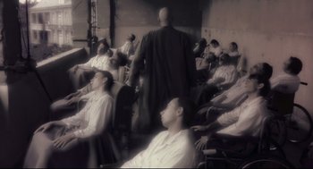 Movie still from “Avalon” (2001), directed by Mamoru Oshii – A group of people sitting in a room; Wide shot, High angle