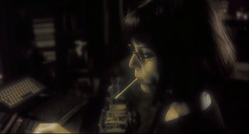 Movie still from “Avalon” (2001), directed by Mamoru Oshii – A woman is smoking a cigarette in front of an open book; Close Up shot, Low angle