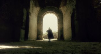 Movie still from “Avalon” (2001), directed by Mamoru Oshii – A person standing in front of an arched doorway; Extreme Wide shot, Low angle