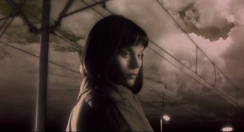 Movie still from “Avalon” (2001), directed by Mamoru Oshii – A woman standing in front of a cloudy sky; Close Up shot, Low angle