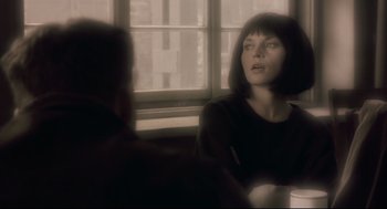 Movie still from “Avalon” (2001), directed by Mamoru Oshii – A woman sitting at a table in front of a window; Close Up shot, Over the shoulder angle