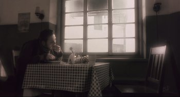 Movie still from “Avalon” (2001), directed by Mamoru Oshii – A person sitting at a table in front of a window; Medium shot, High angle