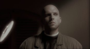 Movie still from “Avalon” (2001), directed by Mamoru Oshii – A man with a bald head wearing a white shirt; Close Up shot, Low angle