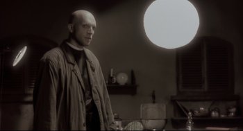 Movie still from “Avalon” (2001), directed by Mamoru Oshii – A bald man standing in front of a mirror; Medium shot, Low angle