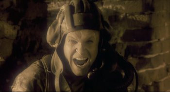 Movie still from “Avalon” (2001), directed by Mamoru Oshii – A man with a helmet on and a mouth open; Close Up shot, Overhead angle