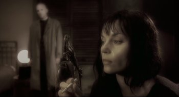 Movie still from “Avalon” (2001), directed by Mamoru Oshii – A woman is holding a cigarette and looking at a statue; Close Up shot, Over the shoulder angle