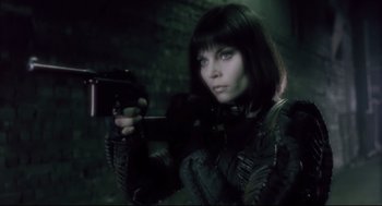 Movie still from “Avalon” (2001), directed by Mamoru Oshii – A woman holding a gun while wearing a black outfit; Close Up shot, Low angle