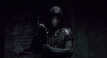 Movie still from “Avalon” (2001), directed by Mamoru Oshii – A woman holding a gun in a dark room; Medium shot, Low angle