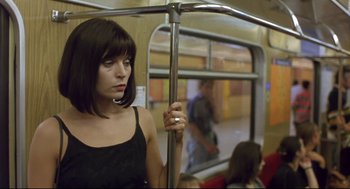 Movie still from “Avalon” (2001), directed by Mamoru Oshii – A woman in a black top is riding a train; Close Up shot, Low angle