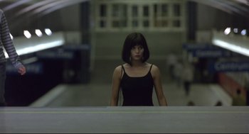Movie still from “Avalon” (2001), directed by Mamoru Oshii – A woman in a black dress standing in front of a building; Medium shot, Low angle