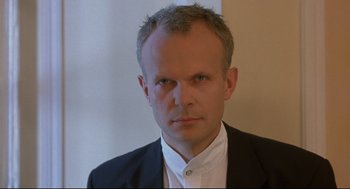 Movie still from “Avalon” (2001), directed by Mamoru Oshii – A person wearing a suit and tie; Close Up shot, Low angle