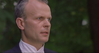 Movie still from “Avalon” (2001), directed by Mamoru Oshii – A person wearing a suit and tie; Close Up shot, Low angle