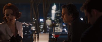 Movie still from “Avengers: Age of Ultron” (2015), directed by Joss Whedon – A man sitting at a table with a drink in front of him; Medium shot, Over the shoulder angle
