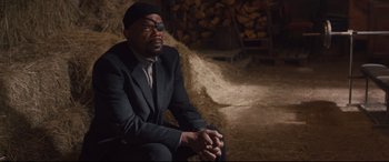 Movie still from “Avengers: Age of Ultron” (2015), directed by Joss Whedon – A man in a suit sitting on a pile of wood; Medium shot, Over the shoulder angle