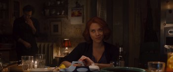 Movie still from “Avengers: Age of Ultron” (2015), directed by Joss Whedon – A woman sitting at a dinner table looking at the camera; Medium shot, Over the shoulder angle