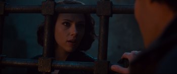 Movie still from “Avengers: Age of Ultron” (2015), directed by Joss Whedon – A woman behind a metal fence looking at the camera; Close Up shot, Over the shoulder angle