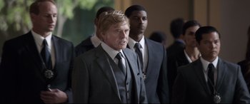 Movie still from “Avengers: Endgame” (2019), directed by Anthony Russo – A man in a suit and tie standing next to another man in a suit and tie; Medium shot, Over the shoulder angle