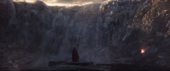 Movie still from “Avengers: Endgame” (2019), directed by Anthony Russo – A man in a red coat sitting in front of a large wave; Extreme Wide shot, Low angle