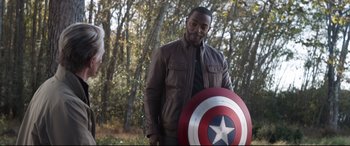 Movie still from “Avengers: Endgame” (2019), directed by Anthony Russo – A man holding a captain america shield in a forest; Medium shot, Over the shoulder angle