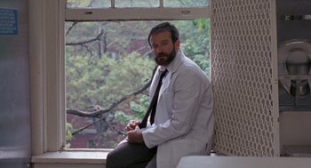 Movie still from “Awakenings” (1990), directed by Penny Marshall – A man in a white lab coat sitting in front of a window; Medium shot, Low angle